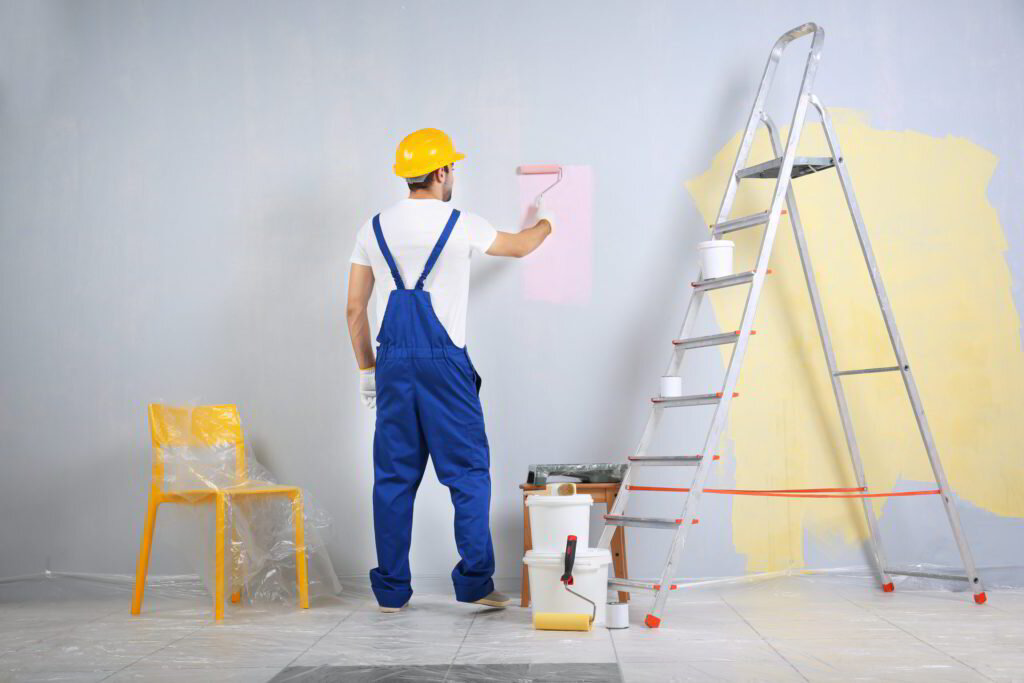 Painter applying a swatch of blue paint to a white wall