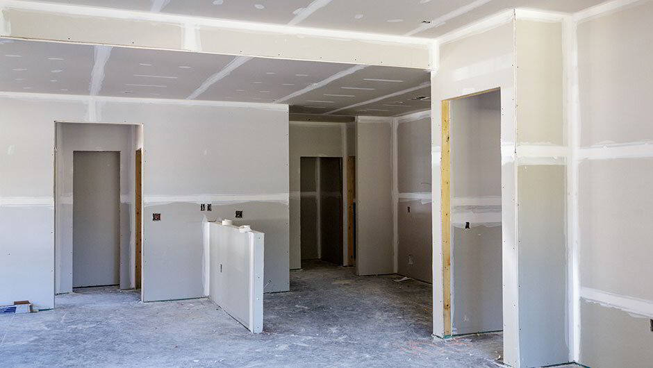Close-up of a person finishing drywall with a taping knife
